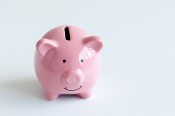 Ceramic pink piggy bank sits on a white surface, symbolizing saving and financial planning for individuals
