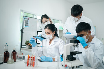 Medical research teamwork in modern laboratory using microscope and blood test tubes for DNA...