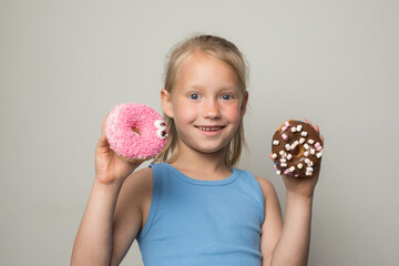 Funny child girl holding testy donut. Cute little girl with sweet food indoor