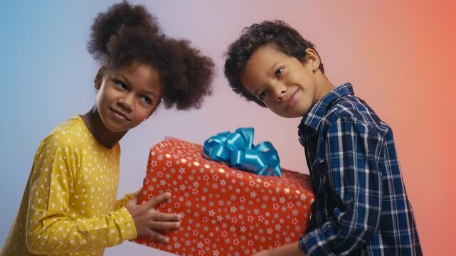 African American siblings shaking gift box, guessing birthday present inside