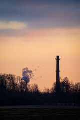 Brick Chimneys in a Natural Landscape with Smoke and Pink-Blue Sunset Sky..