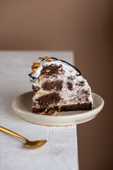 Piece of Pancho cake with pineapple and sour cream topped with chocolate biscuit and walnut on the edge of the table. Vegan dessert. Sugar, lactose and gluten free. Vertical orientation.
