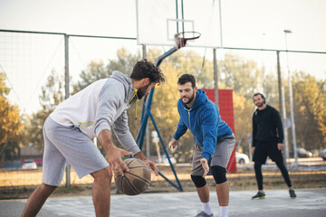 Naklejka premium Group of friends playing basketball outdoors