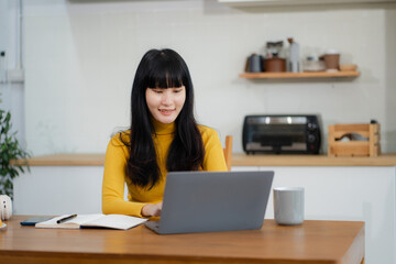 Lifestyle people, using computer working online, doing searching, sitting in the kitchen. Happy...