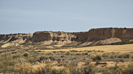  Panoramic view of semi-desert Bardenas Reales in Navarre, Spain. Arid terrain with sparse vegetation. Rugged cliffs and rock formations dominate the background