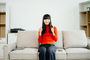 Obraz premium Young asian woman using smartphone and tablet while seated on couch