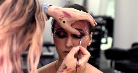 Make-up artist applies makeup to the upper eyelid, close-up. Makeup artist applies a bright eye shadow with a makeup brush.Tutorial master class of professional makeup. 