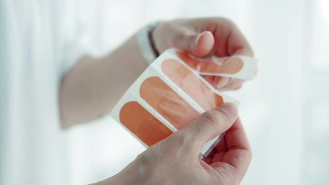 A man in a white T-shirt holds a pack of wound plasters.Body plaster packed in a pack.Foot plaster.Corns, foot, chafed foot