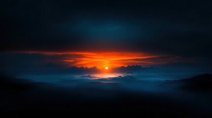 Fototapeta premium A fiery sunset illuminates a cloudy sky over a misty mountain range