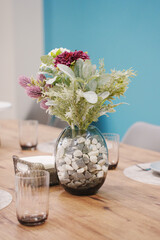 Beautiful floral centerpiece on a wooden dining table with blue wall background