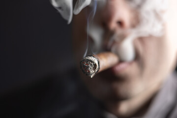 Cuban cigar, Man smoked and holding a cigar in his hand close-up