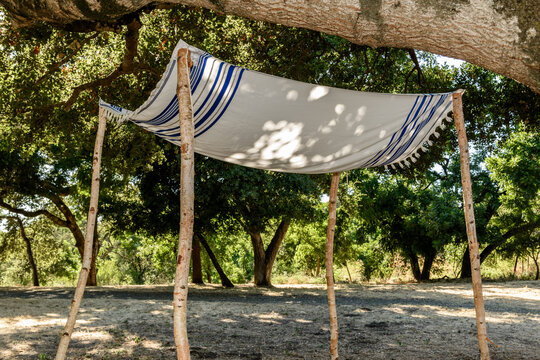 A "chuppah" or Jewish wedding canopy constructed from a prayer shawl and four cut tree wooden poles.