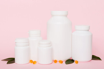 Omega-3 capsules lie in white bottle on a table with green leaves background. Fish oil tablets. Biologically active additives. omega 6, omega 9, vitamin A, E, D, vitamin D3 top view with copy space