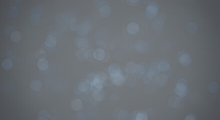 Abstract background with scattered light bokeh.  A multitude of soft, light gray circles creating a diffuse, ethereal effect on a muted gray backdrop