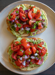 Close-up of fresh avocado toast topped with sliced tomatoes, capers, and parsley, served on a white plate. The dish looks vibrant and delicious, perfect for a healthy breakfast 