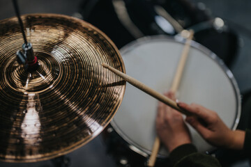 Obraz premium Hands holding drumsticks playing a drum kit and cymbals, illustrating musical creativity in a studio environment.