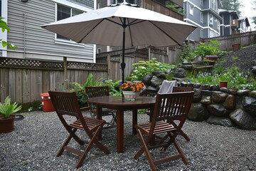 Obraz premium Outdoor dining area with a table and umbrella surrounded by greenery.