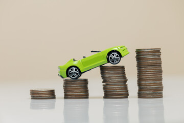 Green Toy Car on Stacks of Coins Representing Financial Growth