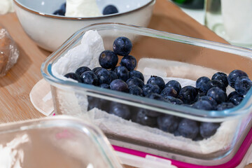 Fresh blueberries stored in glass container on kitchen table.  Ripe blueberries in glass container...