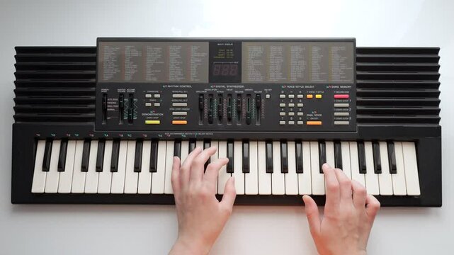 Teenager plays slow melody on electric piano placed on table