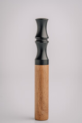 Vertical standing vape device with a black matte mouthpiece and wooden body, isolated on a clean light background with minimalistic presentation..