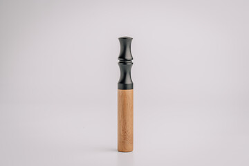 Vertical standing vape device with a black matte mouthpiece and wooden body, isolated on a clean light background with minimalistic presentation..