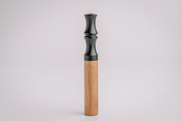Vertical standing vape device with a black matte mouthpiece and wooden body, isolated on a clean light background with minimalistic presentation..