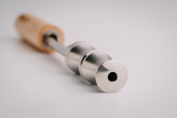 Close-up of a nonelectric smoking pipe with a stainless steel mouthpiece and wooden handle, showing the airflow intake hole at the tip..