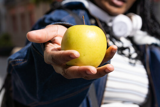 Young student offering a golden delicious apple. Healthy food concept
