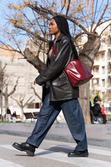 Young woman walking on crosswalk in urban setting