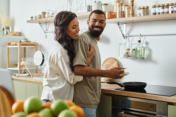 A happy couple enjoys quality time in their comfortable kitchen, cooking and laughing together