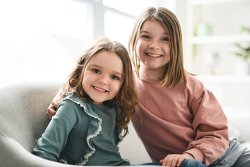 Portrait of two sisters of 6 and 8 years old on sofa