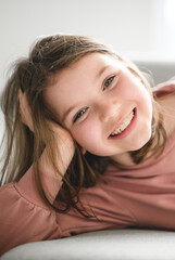 Fototapeta premium Portrait of a cute 8 years old girl on sofa at home