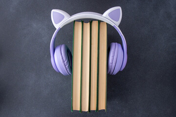 Wireless Headphones with books on black background. Audiobook concept reading and study