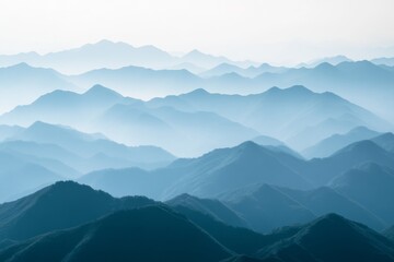 Fototapeta premium A series of misty mountain peaks unfolding in layers under a pale blue sky, showcasing nature's tranquility and the grandeur of the vast landscape.