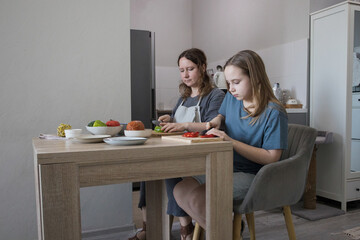 Attractive daughter and her mother cooking in domestic kitchen together, family lifestyle portrait