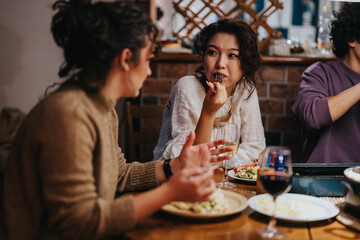 A group of friends seated at a table share dinner, discussion, and drinks in a warm atmosphere. The bonding event highlights connection, camaraderie, and an intimate social setting.