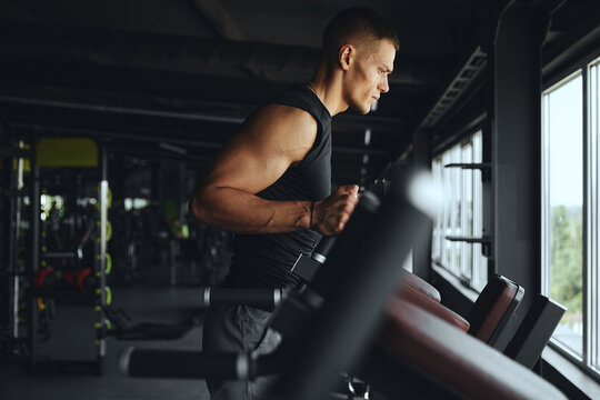 Serious athlete man prepares for an intense workout on the parallel bars, focusing on strength, endurance, and control to enhance his upper body and core stability in the gym.
