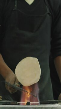 Man cooking street food on a busy street. Chapati is an unleavened flatbread originating from the Indian subcontinent and is a staple in India, Nepal, Bangladesh, Pakistan, Kyrgyzstan, Sri Lanka, the