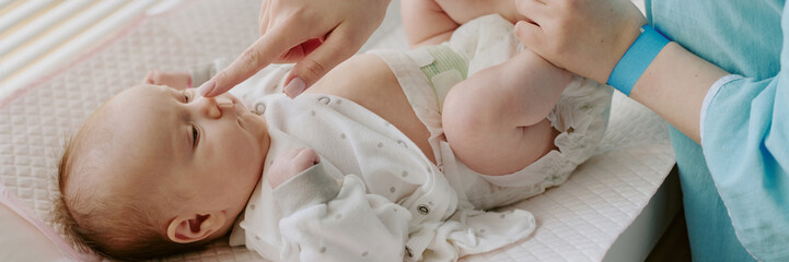 Healthcare professional providing care for newborn infant, using gentle touch and keen attention to health. Baby lies on cushioned surface while receiving essential care