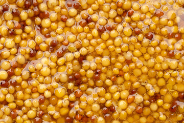 French Dijon mustard in a metal spoon, top view on mustard grains background. Gastronomy concept,...