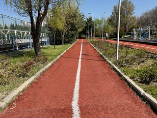 Red track rubber made from crumb and flexible core for running in the park. Garden path outside the apartment building.