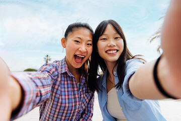 Happy beautiful chinese women friends bonding outdoors in the city - Playful pretty asian female adults meeting and having fun outside, concepts about lifestyle and friendship