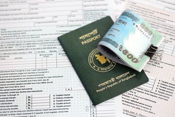 Bangladeshi taka money bills in big amount lies on table with passport and tax forms close up