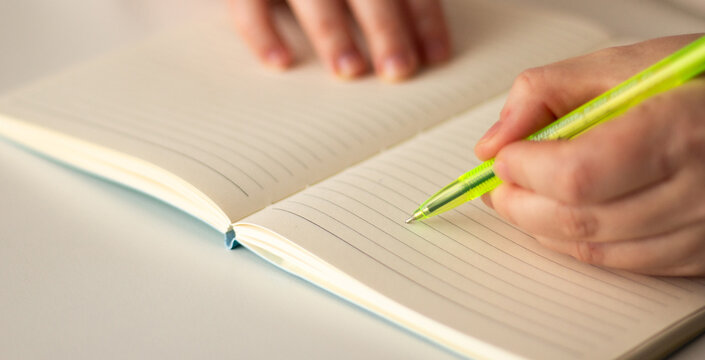 Left handed person making notes on blank page on notebook during psychological session, work conference, business meeting.