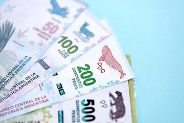 Argentine pesos money bills in big amount lies on teal color table close up