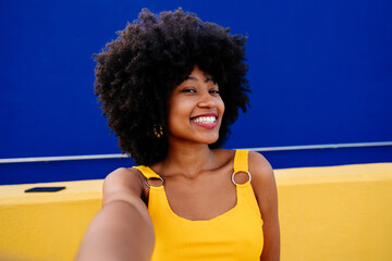 Beautiful young happy african woman with afro curly hairstyle strolling in the city - Cheerful black student girl walking on the street