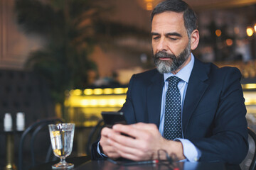 Senior businessman working and having a coffee in coffee bar