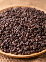 Raw Dark Brown Chickpeas (Kala Chana) on a rustic wooden table. Dry Balck chickpea (ceci neri) background close up.