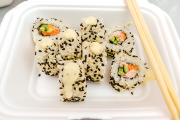 Set of fish sushi rolls with salmon,sesame in plastic disposable food container box. Seafood, Food delivery,take out service from restaurant concept.